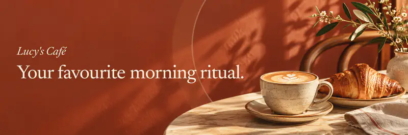Lucy's Café: Your favourite morning ritual. A latte and croissant on a marble table in warm morning light.